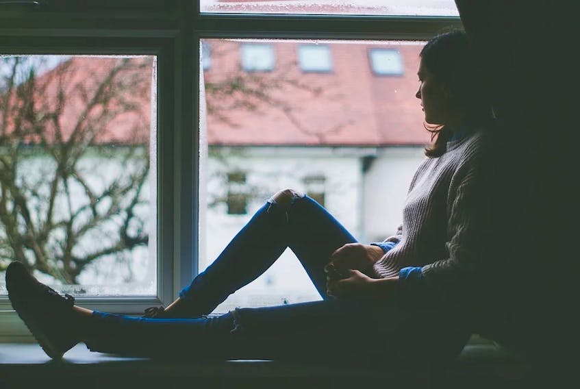 Stock photo from pixabay.com of woman sitting alone, looking out a window.