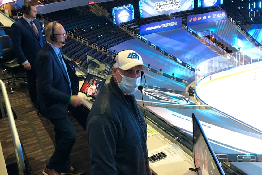 With no fans at Rogers Place, Sportsnet colour commentator Louie DeBrusk, left, play-by-play voice Chris Cuthbert and in-game stats man David Moir call an NHL playoff game from their makeshift booth in the seating area instead of higher up in the press box.