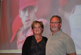 Dianne MacLean and her husband, Irwin, stand on stage before their presentation about their son Mitch (featured behind). MacLean presented at the International Children's Memorial Place fundraiser dinner on Saturday.