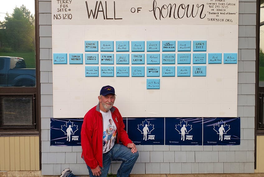Ford Green kneels in front of the Wall of Honour memorial erected in Baddeck for the 40th annual Terry Fox Run on Sept .20, which has gone viral this year due to the COVID-19 pandemic. For 30 years, Green has volunteered at the Terry Fox Run in Baddeck and is currently the run co-ordinator for the area. Wanting to find a way to commemorate four decades of runs held in honour of Terry Fox's Marathon of Hope, Ford came up with the idea of a Wall of Honour that pays tribute to loved ones and raises money for cancer research. Partnering up with the Lion's Club in Baddeck, the wall is located outside the Co-Op store and more plaques in memory of people who have died by cancer are being added daily. CONTRIBUTED 