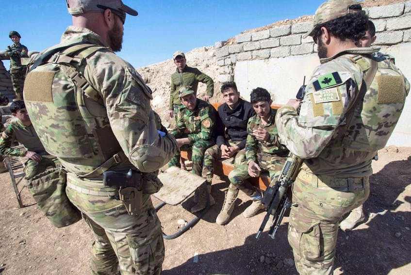 File photo from 2017 of Canadian special forces soldiers, left and right, speak with Peshmerga fighters at an observation post, Monday, February 20, 2017 in northern Iraq. 