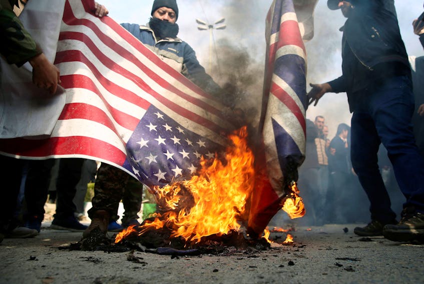 Demonstrators burn the U.S. and British flags during a protest against the assassination of the Iranian Major-General Qassem Soleimani, head of the elite Quds Force, and Iraqi militia commander Abu Mahdi al-Muhandis who were killed in an air strike in Baghdad airport, in Tehran, Iran January 3, 2020.