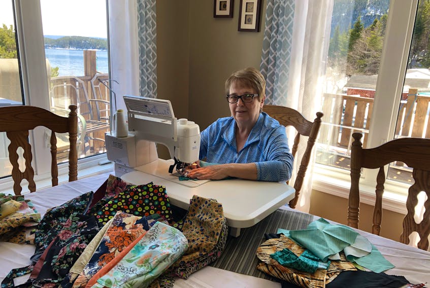 June Wells is pictured at her sewing machine in her Jackson’s Arm home surrounded by material and scrub hats that she’s making and donating to workers with Western Health. 
Contributed
