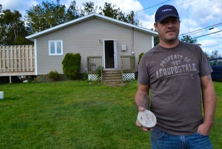 Jamie Matthews displays the basic smoke alarm that he says saved his life Thursday evening after a fire started in the basement of his Union home.
