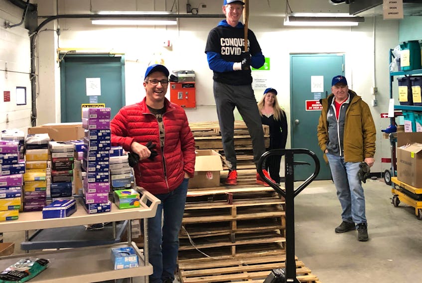 Broadcaster Jamie Campbell (second from left, standing on palettes) pitches in earlier this month at Timmins and District Hospital in the northern Ontario city, where Campbell delivered personal protective equipment from Toronto as part of the COVID-19 medical relief effort.
