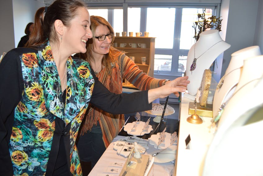 Tasha Matthews, left, jewelry artist and owner of Tasha Grace Designs, shows Jenni MacLean, from the Gaelic College in St. Anns, one of her favourite pieces at the Cape Breton Centre for Craft & Design in Sydney on Thursday. The Cape Breton Centre was hosting its fifth annual Craft Connect Buyers’ Market in the centre’s loft, an opportunity for retailers around the island to purchase Cape Breton handmade products for their stores and gift shops. A total of 12 professional craft producers participated. Matthews, who describes her jewelry as "handmade pieces that look like poetry," said this is her favourite piece, as it's the best expression she has made of spirit so far. Sharon Montgomery-Dupe/Cape Breton Post