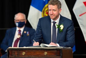 Nova Scotia Premier Iain Rankin, accompanied by Lt.-Gov. Athur LeBlanc, left, signs his oath of office in Halifax on Tuesday, Feb. 23, 2021. Rankin replaces Stephen McNeil who  announced last summer he was stepping down after 17 years in politics. THE CANADIAN PRESS/Andrew Vaughan