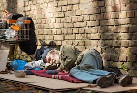 A sleeping homeless man lying on cardboard. STOCK IMAGE