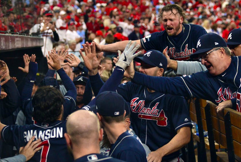 Atlanta Braves shortstop Dansby Swanson, bottom left, celebrates with third baseman Josh Donaldson, top right, and teammates after scoring against the St. Louis Cardinals during the ninth inning in game three of the 2019 NLDS playoff baseball series at Busch Stadium. (Jeff Curry-USA TODAY Sports)