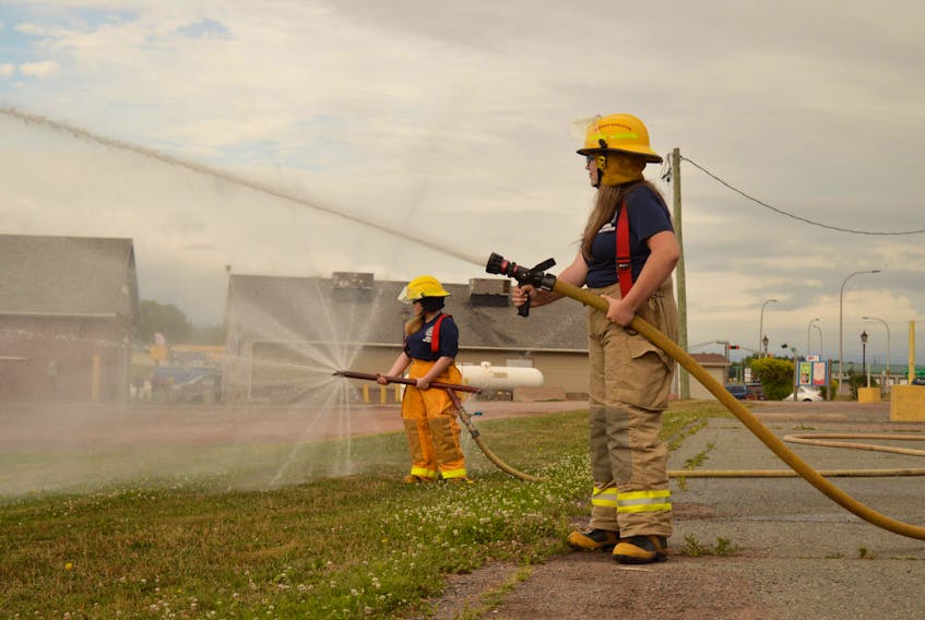Junior firefighters Anna Jesulaitis, left, and Macelynn Dwyer practise with the Borden-Carleton Fire Department.
