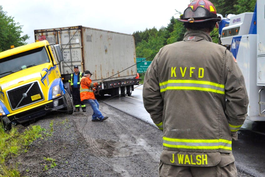 Tow truck cables are hooked beneath the frame of a transport truck on June 25 after it slid into and became stuck in the highway embankment along Highway 101 westbound, near marker 217 and exit 13.
