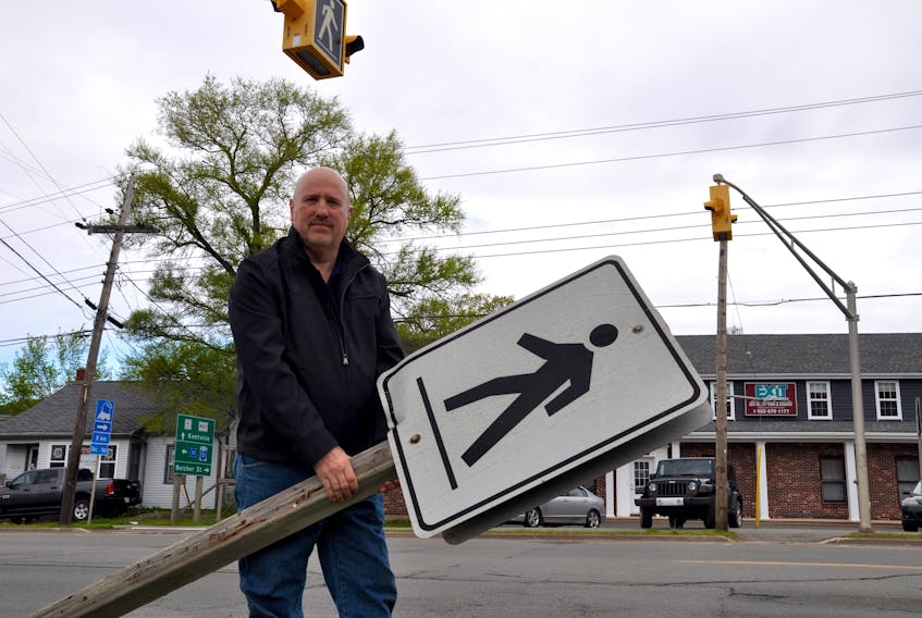 Dan Bartie holds a pedestrian sign that lay on the ground, broken, in front of his New Minas home on Commercial Street until it was righted a few days ago by the province's transport department after an email conversation with Kings County News.