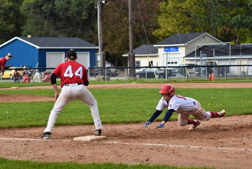 Acadia’s Tiernan MacDonald dives back to first base in a race against an incoming pass from the opposing pitcher.