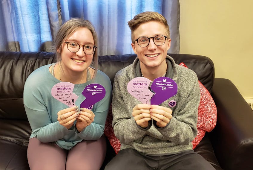 Students Sydney Rankin and Benjamin Palmer with broken hearts made of paper carrying  messages about mental health introduced as part of the Canadian Alliance of Students Associations’ national #StudentsLetsAct campaign.