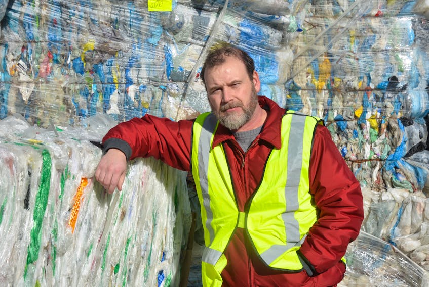 Valley Waste Resource Management communications manager Andrew Garrett with one of the growing stockpiles of plastic bags and film sitting outside the Scotia Recycling facility in Kentville.