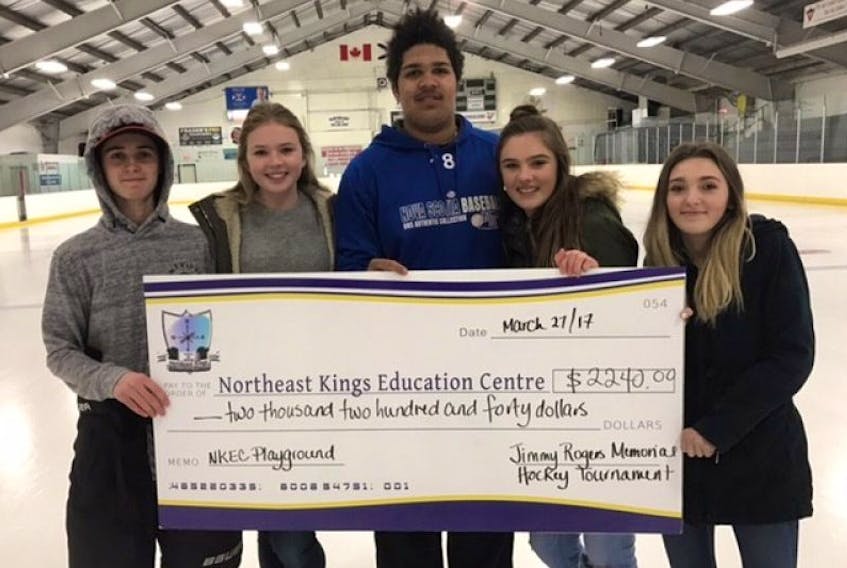 NKEC students Cole Phillips, left, Emma Taylor, Dyton Blackett, Gracie Taylor and Emelie Bennett receive a cheque to help cover the costs of a new playground during the Jimmy Rogers Memorial Hockey Tournament in Canning.