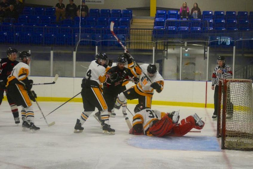 East Hants goalie makes a dive save while Devon Pennell, number 60 with the Avon River Rats races for the puck.