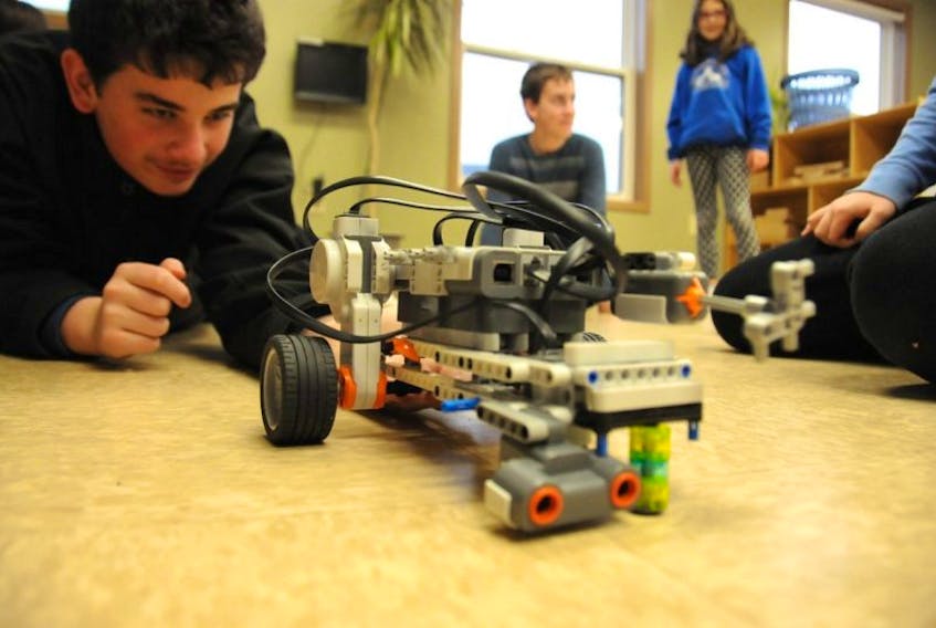 <p>Dylan Moase checks some equipment on his group’s First Lego League robot during a meeting of the Kensington robotics club Thursday evening.</p>