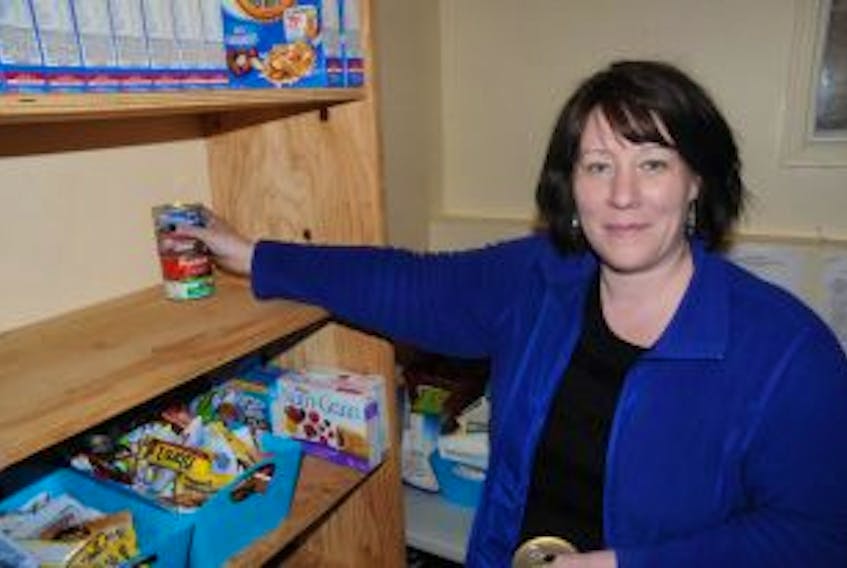 ["President of the Carbonear chapter of the Society of St. Vincent de Paul, Kerri Abbott, helps place donated items on the organization's nearly empty shelves."]