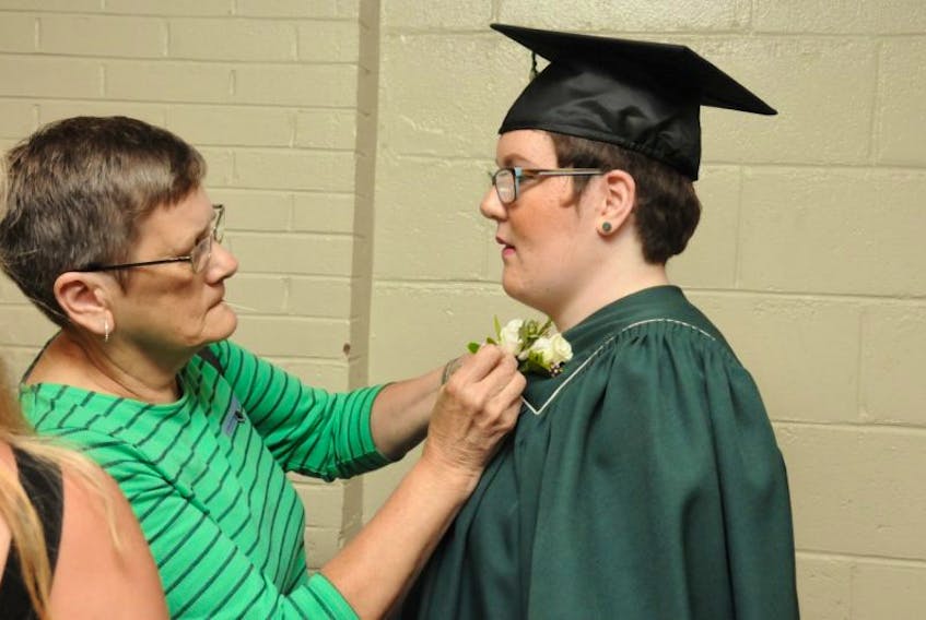 <p>Hailliegh Mill, right, gets some help with her corsage from her grandmother Evelyn Mill Friday night, just before she and the rest of her class of 44 Kensington Intermediate Senior High graduates took to the stage.&nbsp;</p>