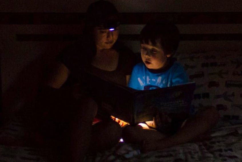 <p>Kitrin Jeffrey reads to her son by the light of a headlamp during the power outage.</p>