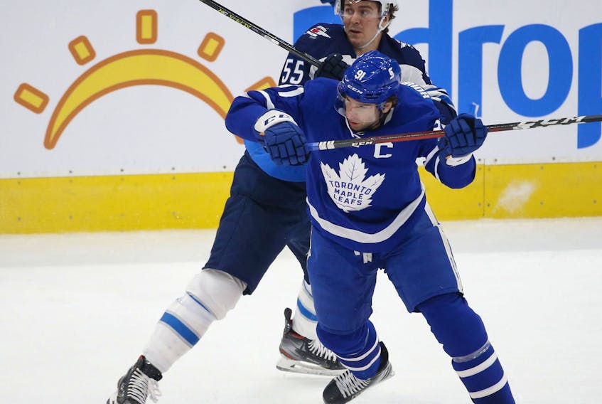 Jets' Mark Scheifele  checks Maple Leafs' John Tavares  during the first period in Toronto on Monday.