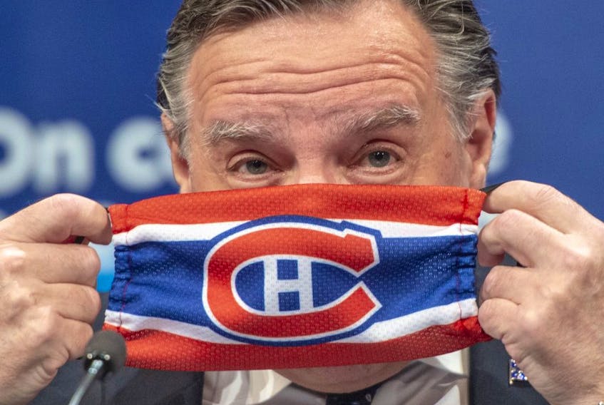 Quebec Premier Francois Legault puts on a Montreal Canadiens face mask as he finishes the daily COVID-19 press briefing, Thursday, May 21, 2020 in Montreal.