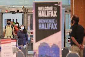 Air passengers arriving from a flight from St. John's speak to a member of provincial heath enforcement staff, in the baggage area of Halifax Stanfield International Airport last week. SALTWIRE FILE PHOTO