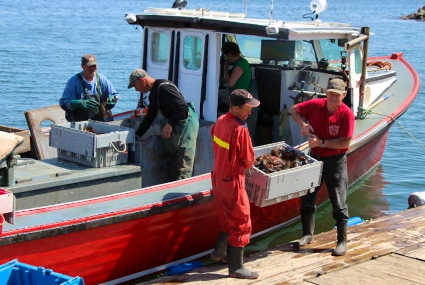Charlie Landry, left, and Andrew Lynch, right, both employees of North Nova Seafoods help unload Wayne Grealey's catch in Caribou, Pictou County