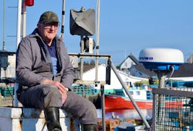 Edwin Nickerson watches from atop of the wheelhouse while the crew load lobster traps aboard the fishing vessel Haw at the Clark’s Harbour wharf on dumping day 2019. 