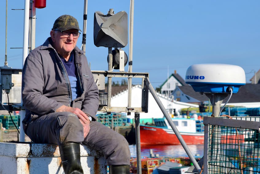 Edwin Nickerson watches from atop of the wheelhouse while the crew load lobster traps aboard the fishing vessel Haw at the Clark’s Harbour wharf on dumping day 2019. 