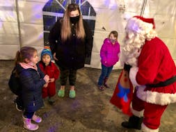 Santa hands a candy cane to four-year-old Callie Sharpe from Bateston, who was at Louisbourg's Christmas village with her mother. NICOLE SULLIVAN • CAPE BRETON POST