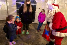 Santa hands a candy cane to four-year-old Callie Sharpe from Bateston, who was at Louisbourg's Christmas village with her mother. NICOLE SULLIVAN • CAPE BRETON POST