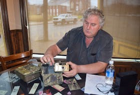 Al Muir shows off an early model of trail camera that used 35 mm film and required the use of a flash. 
