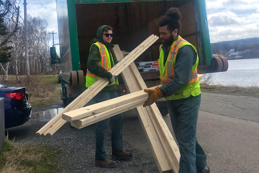 Kent Building Supplies employees Austin Sullivan, left, and Joseph Pelly deliver some lumber to a home in Westmount on Thursday. Local building supply stores have been busy filling orders as people self-isolating in their homes make repairs and touchups, or begin new projects. Kent and most other stores are offering free delivery. Chris Connors/Cape Breton Post

