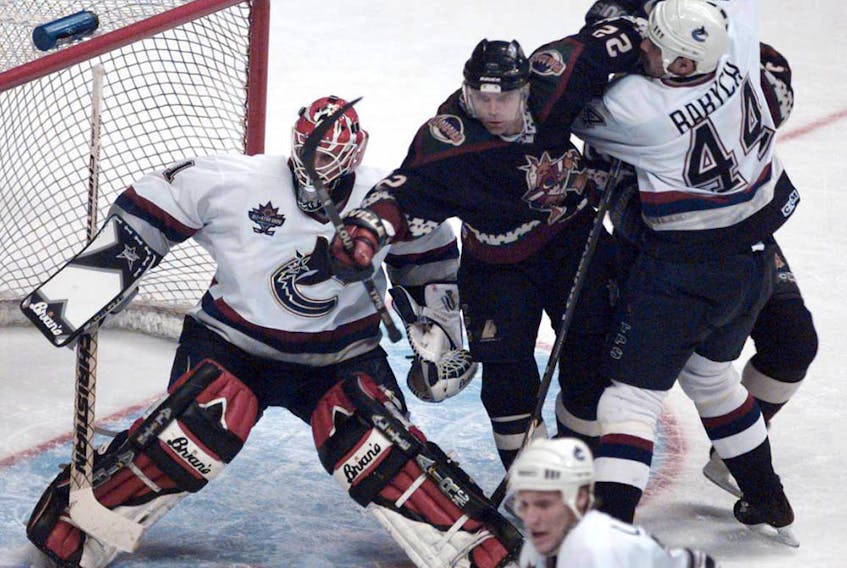 Canucks Dave Babych takes out Phoenix Coyotes Mike Gartner in front of goalie Sean Burke at GM Place in Vancouver. on Jan. 21, 1998. 