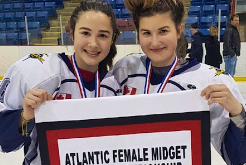 Sisters Kara (left) and Ella MacLean, first-year players with the Northern Subway Selects, hold the 2018 Atlantic Female Midget ‘AAA’ Hockey Championship banner. The Selects will skate for a national title, from April 22 to 28, at the Esso Cup in Bridgewater. Contributed
