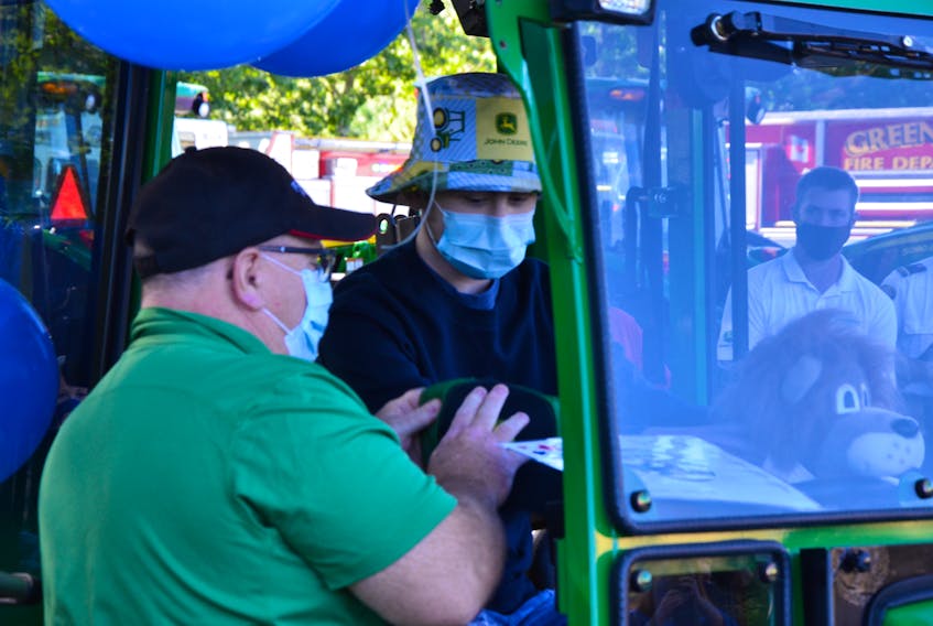With his dad Jeff Davies looking on, 17-year-old Wyatt Davies sits in his new climate-controlled tractor cab for the first time. This was part of a wish for tractor accessories granted by Make-A-Wish Canada. KIRK STARRATT