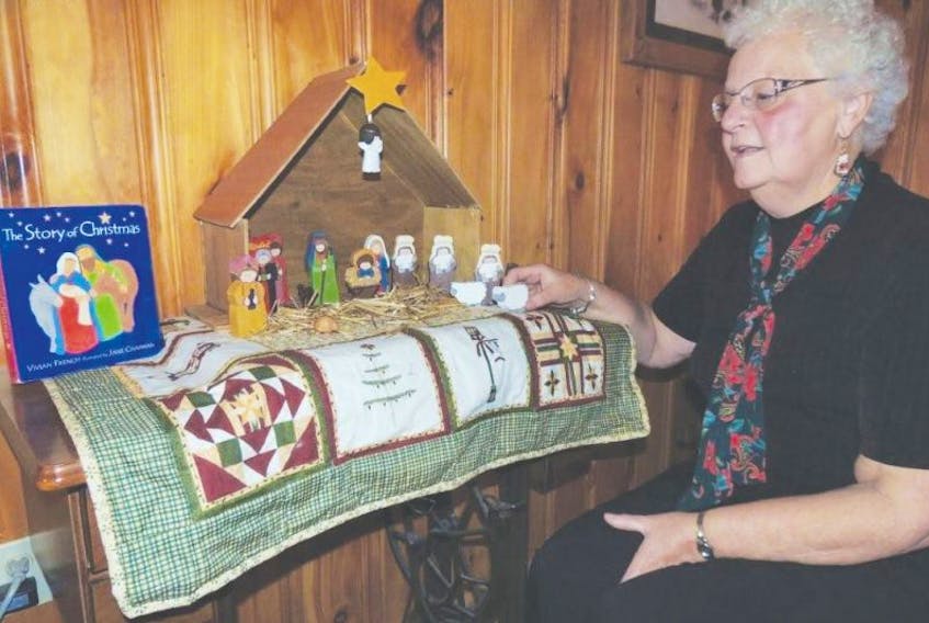 <p>Margie Beck adjusts the figures in a nativity set she made for her granddaughter Marleigh. She wanted it to be a very personal gift so the shingles that make the manger roof come from an old family barn and the quilt on which it sits was stitched by Beck's sister. (Rosalie MacEachern photo)</p>