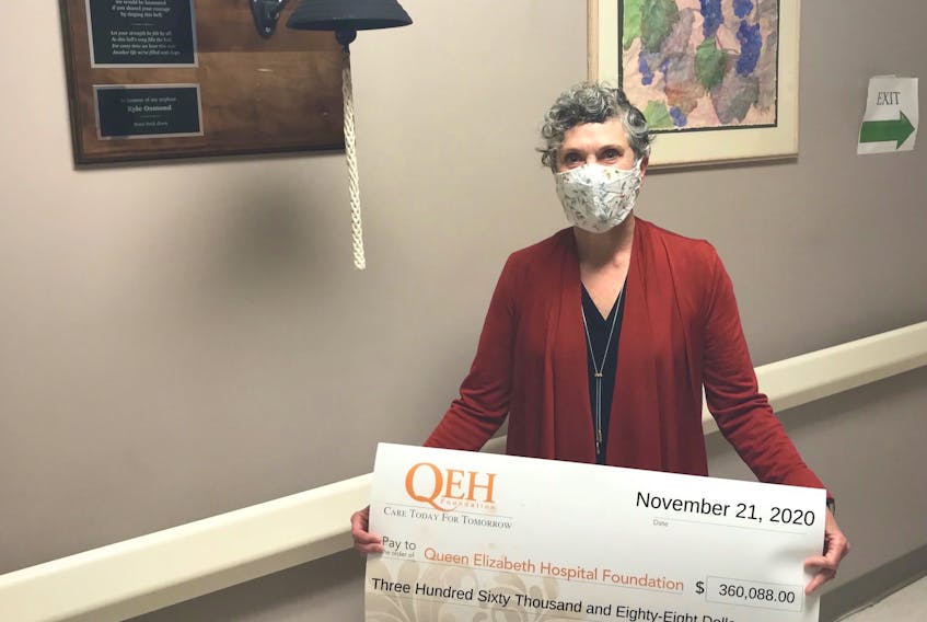 Patsy MacLean, QEH Foundation chairwoman, holds the cheque for $360,088 from Saturday's QEH Foundation Mask-Q-rade Elimination Draw and Auction. MacLean is standing next to the P.E.I. Cancer Treatment Centre oncology bell. A similar one was purchased for pediatrics.