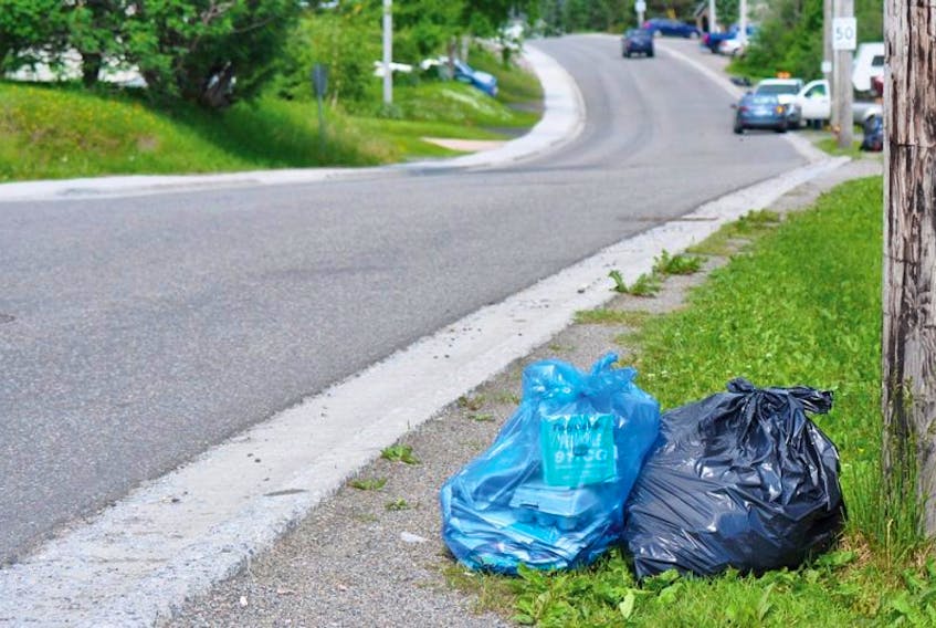 A blue bag of recyclables is seen next to a garbage bag awaiting collection on Massey Drive on Thursday, July 10, 2014. The Town of Massey Drive implemented a recycling program last month.
