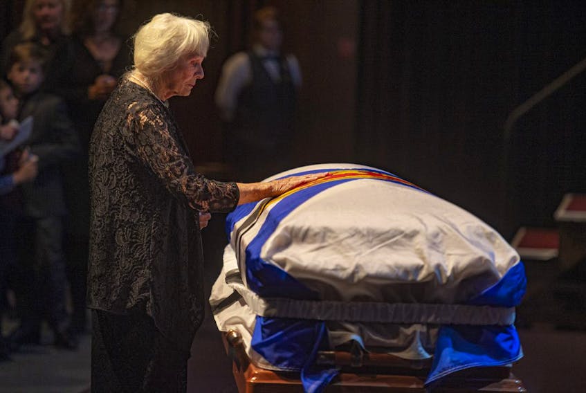 Mavis Buchanan places a hand on her husband's casket during a celebration of life for former premier John Buchanan on Friday at the Rebecca Cohn Auditorium in Halifax.