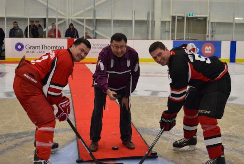 Senator Dan Christmas, centre, is shown dropping the ceremonial puck to officially kick off the Mi'kmaq Heritage Hockey Classic to Chief Leroy Denny of Eskasoni, left, and Geoff MacLellan, Minister of Transportation and Infrastructure Renewal, prior to Saturday’s game at the Membertou Sport and Wellness Centre. 