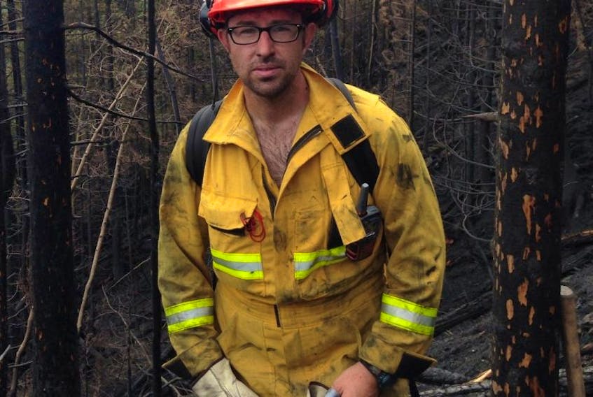 Firefighter Mike Montigny stands next to the charred remains of a wooded area in the Mt. McAllister area north of Prince George, B.C.