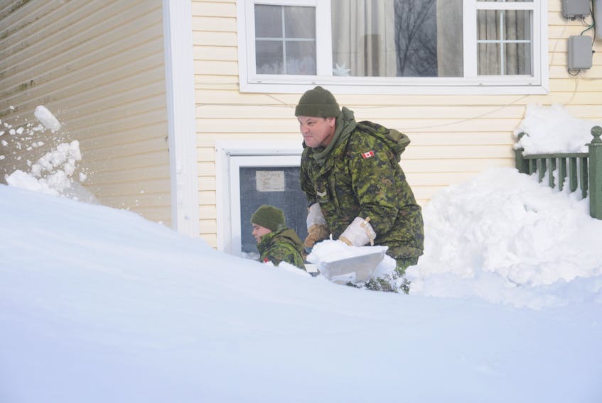 Pte. Roman Crummey (left) and Cpl. Pat Breen of the Royal Newfoundland Regiment were hard at work digging out the front door of a basement apartment on Franklyn Avenue in St John's Monday. ANDREW ROBINSON/THE TELEGRAM