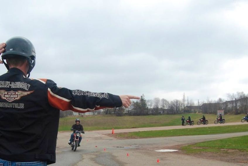 Instructor Aaron Glode signals the direction that one of the Gearing Up motorcycle training program students should take at the last minute to avoid an imaginary collision.