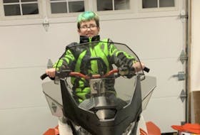 Tyson Ryan’s son Miguel sits on the snowmachine his father has ready for Cain’s Quest 2020. CONTRIBUTED