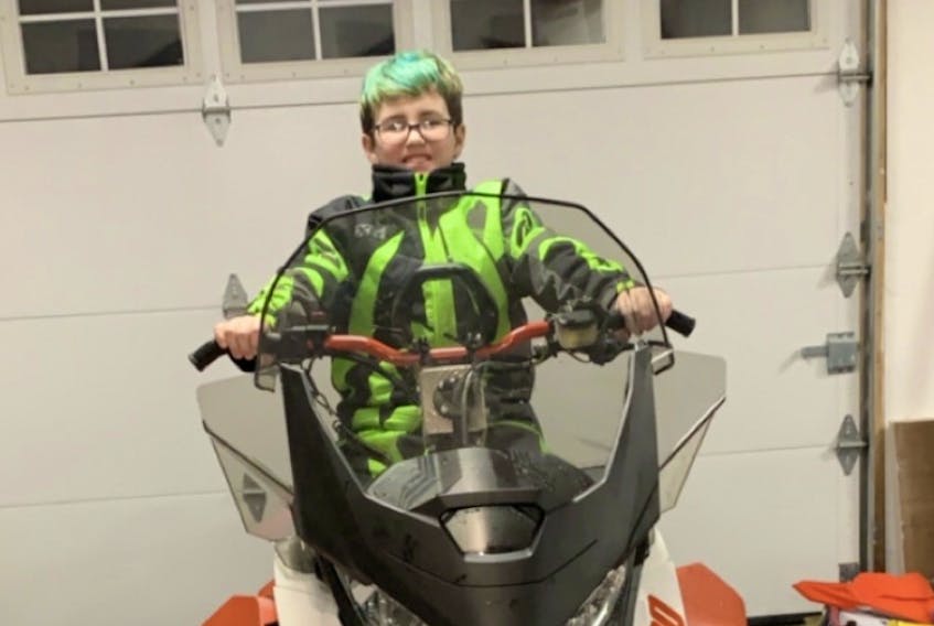Tyson Ryan’s son Miguel sits on the snowmachine his father has ready for Cain’s Quest 2020. CONTRIBUTED