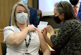 Ellen Foley-Vick, a registered nurse with public health, is given the first COVID-19 vaccination for the province by Chief Medical Officer of Health Dr. Janice Fitzgerald on Dec. 16. Telegram file photo