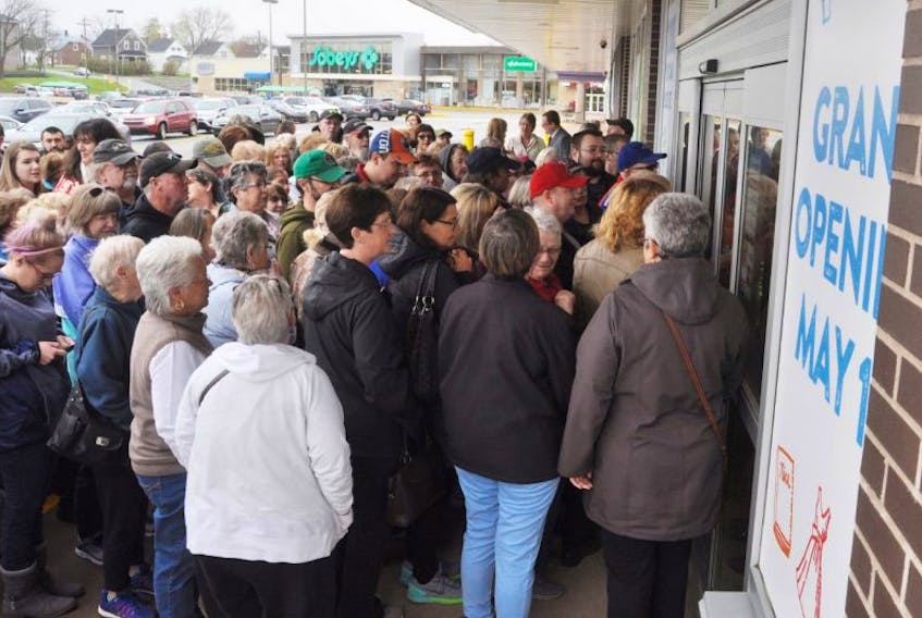 Dozens of customers anxiously wait for the doors of Value Village to open.
